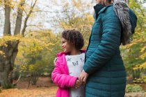 Happy daughter holding hands with mother in autumn woods — Stock Photo