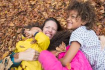 Retrato feliz madre y niños jugando en hojas de otoño - foto de stock