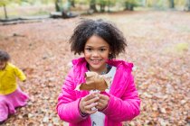 Retrato menina feliz segurando folha de outono em madeiras — Fotografia de Stock