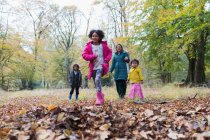 Familia feliz corriendo y jugando en los bosques de otoño - foto de stock