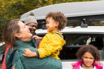Feliz família abraçando fora do carro no estacionamento — Fotografia de Stock