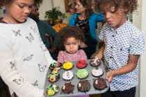 Brother and sisters holding decorated Halloween cupcakes — Stock Photo