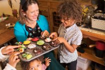 Feliz madre e hijos con cupcakes de Halloween decorados - foto de stock