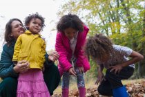 Madre felice e bambini che giocano in foglie autunnali — Foto stock