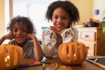 Portrait happy brother and sister carving pumpkins at table — Stock Photo