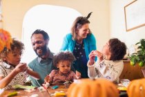 Família feliz decorar cupcakes de Halloween à mesa — Fotografia de Stock