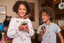 Retrato irmão feliz e irmã com cupcakes de Halloween decorados — Fotografia de Stock
