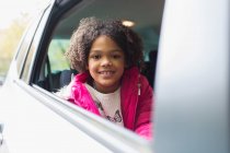 Retrato menina feliz montando no banco de trás do carro — Fotografia de Stock