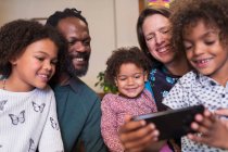 Familia multiétnica feliz usando el teléfono inteligente - foto de stock