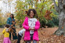 Portrait happy girl playing with family in autumn leaves — Stock Photo