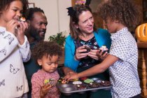 Багатоетнічна сім'я їсть прикрашені кекси на Хеллоуїн — стокове фото