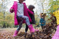Игривые дети, пинающиеся осенними листьями — стоковое фото