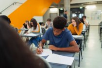Konzentrierte Gymnasiastin macht Prüfung am Schreibtisch — Stockfoto