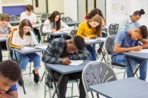 Étudiants du secondaire ciblés qui passent des examens dans des bureaux en classe — Photo de stock