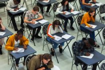 Estudiantes de secundaria enfocados que toman exámenes en escritorios en el aula - foto de stock