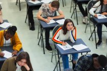 Задумчивая школьница сдает экзамен за партой в классе — стоковое фото