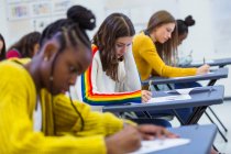 Konzentrierte Gymnasiastinnen bei der Prüfung am Schreibtisch im Klassenzimmer — Stockfoto