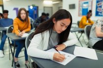 Focused high school girl student taking exam at desk in classroom — Stock Photo