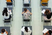 Estudiantes de preparatoria de vista aérea que toman examen en escritorios en el aula - foto de stock