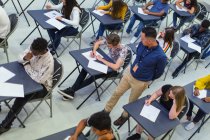 Lehrer beaufsichtigt Gymnasiasten bei Prüfungen am Schreibtisch — Stockfoto