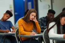 Estudante do ensino médio focado fazendo exame na mesa em sala de aula — Fotografia de Stock