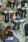 Estudantes do ensino médio fazendo exame em mesas — Fotografia de Stock