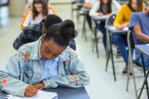 Сосредоточенные школьницы сдают экзамен за партой в классе — стоковое фото