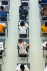 Vista desde arriba de los estudiantes de secundaria que toman examen en los escritorios en el aula - foto de stock