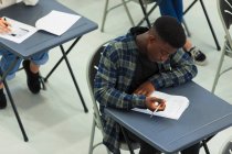 Estudiante de secundaria enfocado tomando examen en el escritorio en el aula - foto de stock
