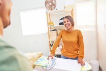 Femme heureuse repassage vêtements à la maison — Photo de stock