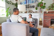 Пара розмовляє і читає на дивані вітальні — стокове фото