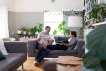 Счастливая зрелая пара с помощью цифрового планшета на диване гостиной — стоковое фото