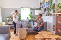 Playful mature couple folding laundry in living room — Stock Photo