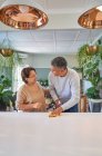 Heureux mature couple nettoyage cuisine îlot et parler — Photo de stock