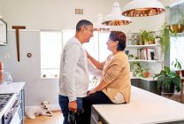 Happy affectionate mature couple talking in kitchen — Stock Photo
