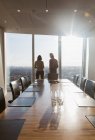 Geschäftsleute stehen am sonnigen Konferenzzimmerfenster — Stockfoto