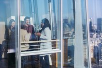 Empresários conversando na ensolarada janela do escritório urbano — Fotografia de Stock