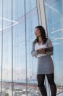 Продумана бізнес-леді з цифровим планшетом у високогірному офісному вікні — стокове фото