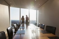 Geschäftsleute unterhalten sich am sonnigen Konferenzzimmerfenster eines Hochhauses — Stockfoto
