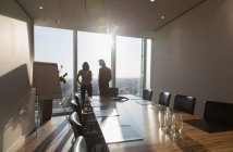 Business people talking at sunny highrise conference room window — Stock Photo