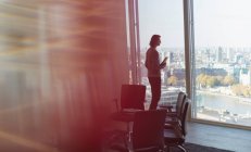 Задумчивый бизнесмен, стоящий у окна высотного офиса — стоковое фото