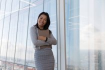Porträt selbstbewusste Geschäftsfrau mit digitalem Tablet am Hochhausfenster — Stockfoto