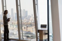 Продуманий бізнесмен стоїть у вікні міського високогірного офісу — стокове фото