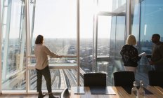 Businesswomen standing at sunny urban highrise office window — Stock Photo