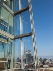 Uomo d'affari che utilizza lo smart phone alla soleggiata finestra dell'ufficio del grattacielo urbano — Foto stock