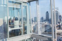 Ділові люди говорять у сонячному міському високогірному офісному вікні — стокове фото