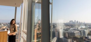 Sorridente donna d'affari in soleggiata finestra ufficio grattacielo urbano — Foto stock