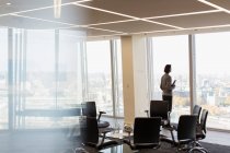 Nachdenklicher Geschäftsmann am sonnigen Bürofenster eines Hochhauses — Stockfoto