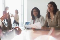 Mulheres de negócios ouvindo na sala de reuniões ensolarada — Fotografia de Stock
