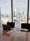 Laptop und Papierkram auf Konferenztisch mit Blick auf die Stadt — Stockfoto